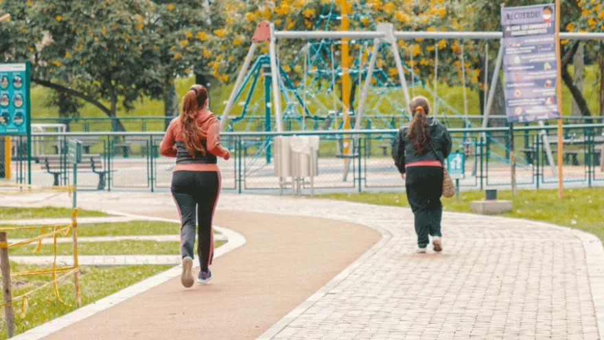 Two women jog together in a park, enjoying the fresh air and physical activity.