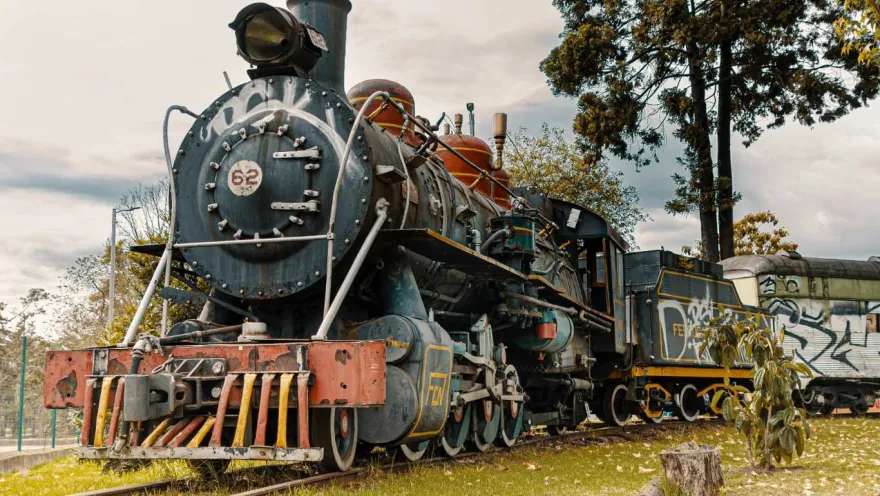 An old train on the tracks, covered in colorful graffiti and weathered by time.