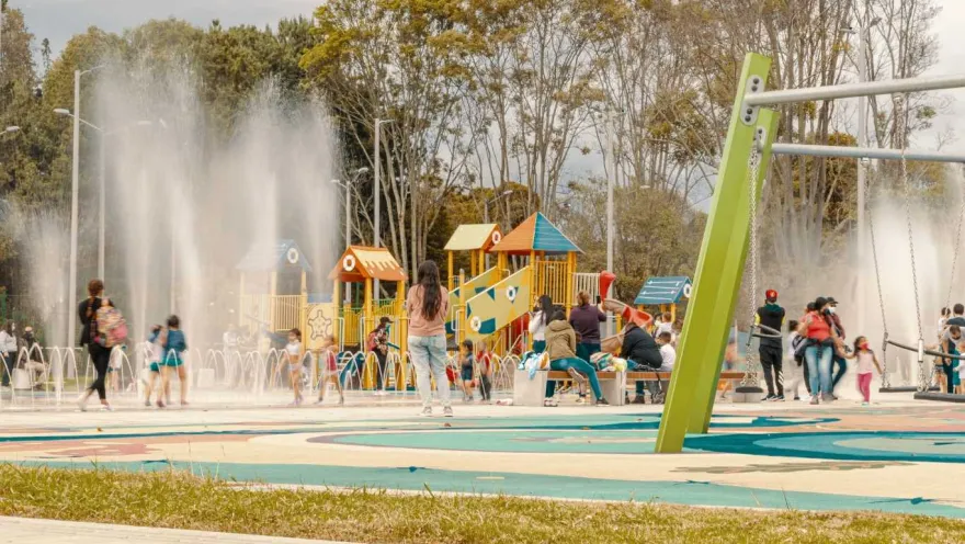 Children playing in the water in a park, laughing and enjoying a sunny day.