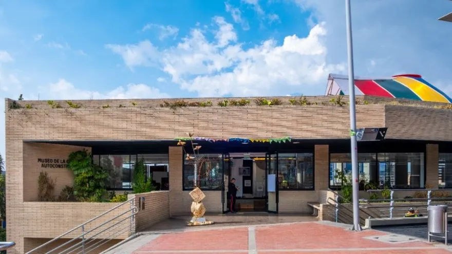 Fachada del Museo de la Ciudad Autoconstruida, edificio de ladrillo con entrada principal, rampas y cielo despejado.