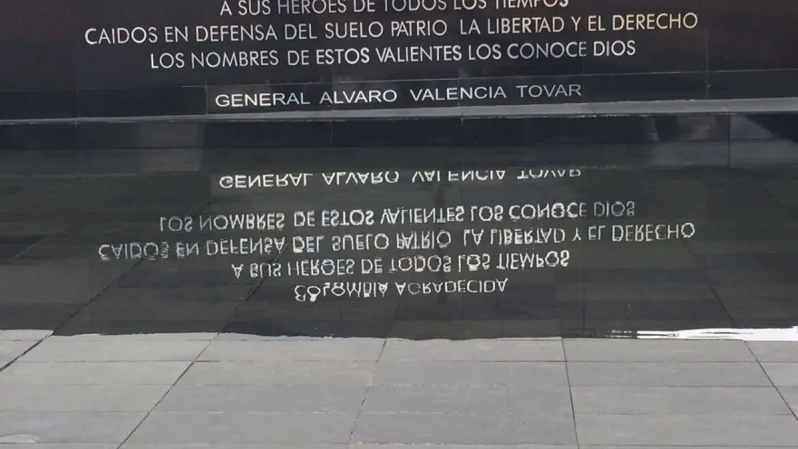 Placa conmemorativa a héroes caídos con inscripción visible en mármol negro y letras blancas con su reflejo en agua. Hay una leyenda que dice: “COLOMBIA AGRADECIDA A SUS HÉROES DE TODOS LOS TIEMPOS CAÍDOS EN DEFENSA DEL SUELO PATRIO, LA LIBERTAD Y EL DERECHO LOS NOMBRES DE ESTOS VALIENTES LOS CONOCE DIOS. GENERAL ÁLVARO VALENCIA TOVAR”