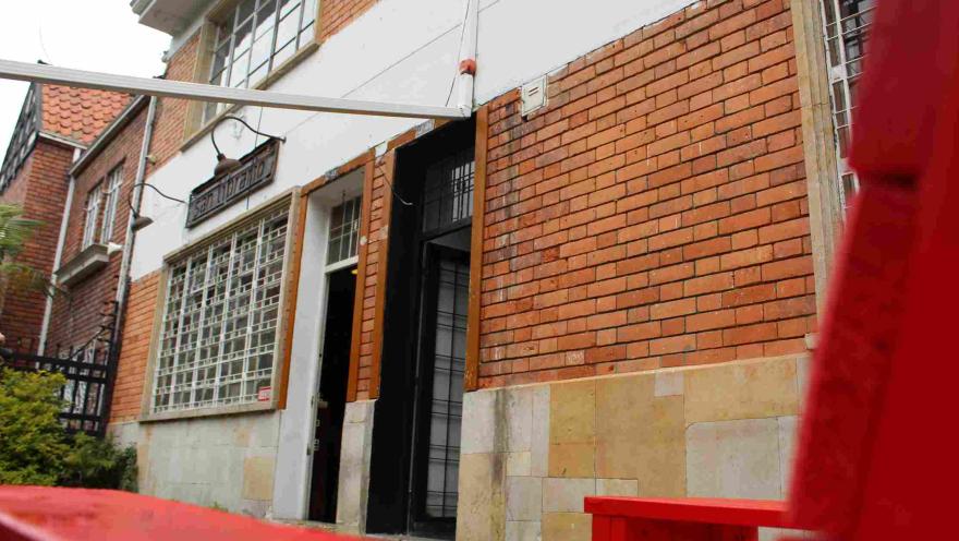 Entrance of the San Librario bookstore with a brick facade, featuring a red bench in the foreground.