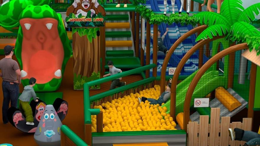 Jungle-themed children's play area with slides, a ball pit, and animal figures such as a zebra, lion, and monkey, with children playing in the space.