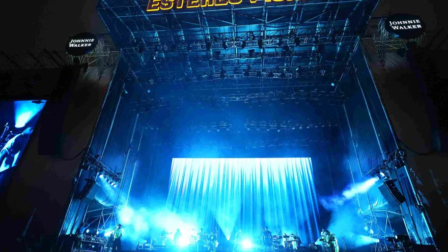The main stage of Estéreo Picnic illuminated in blue, with a live band and a large screen in the background.