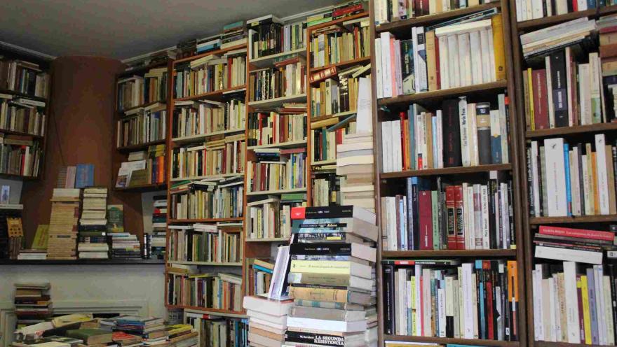 Bookstore filled with tall shelves full of books and stacks piled on the floor.