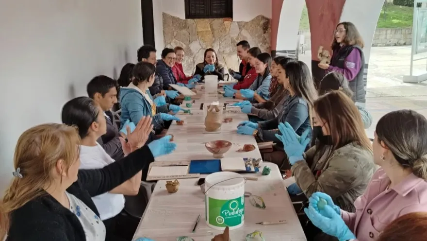  Un grupo de personas sentadas a una mesa, todas usando guantes, conversando y compartiendo ideas.