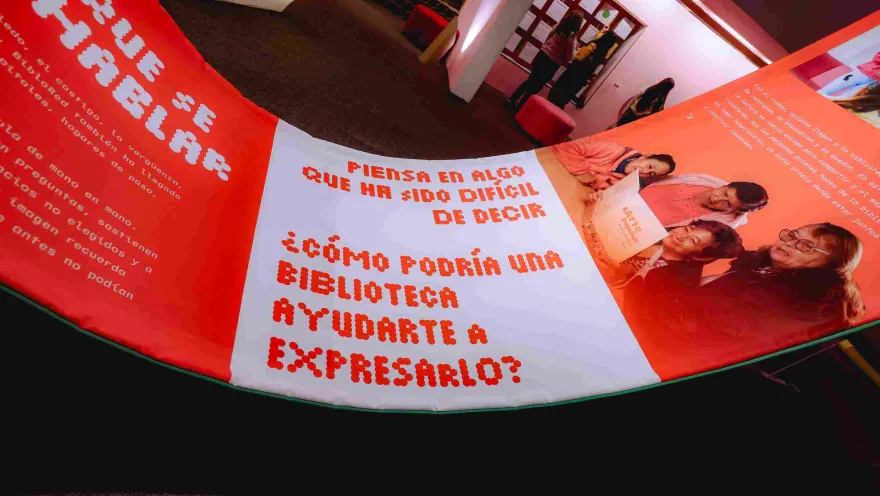 An interactive installation featuring messages about the power of libraries and personal expression, displayed in a space illuminated with warm red and orange tones during a cultural showcase.