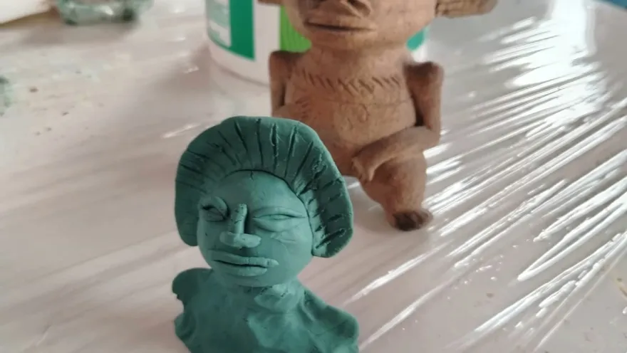  Escultura de arcilla que representa a una mujer y un hombre en una pose íntima y expresiva.