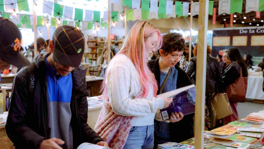 Visitors browse and explore books at a literary fair booth, amidst a cultural setting filled with passionate readers, publishers, and literary activities.