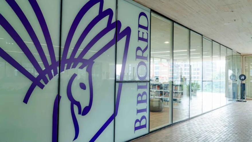 A library facade with glass walls and a purple hummingbird graphic design, identifying the space as a modern and cultural venue.