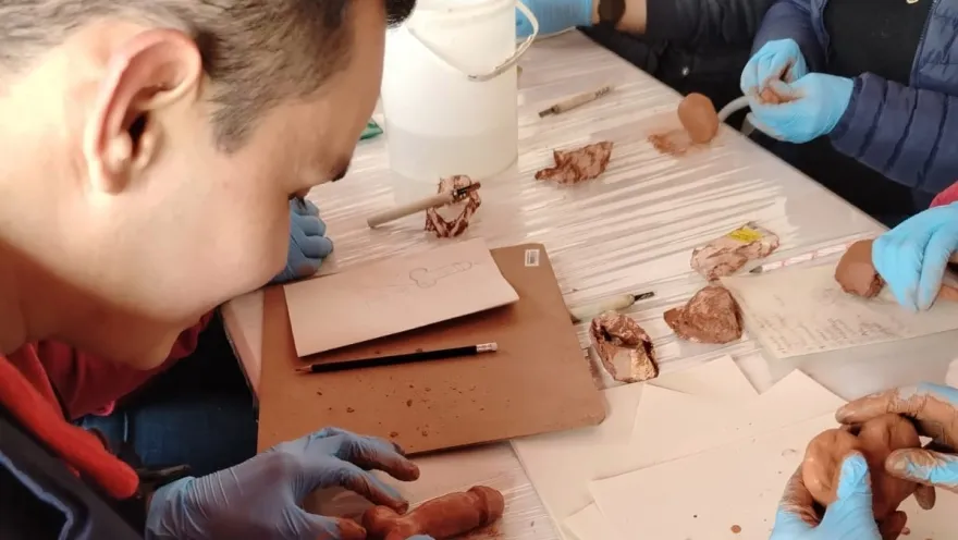  Un grupo de personas modelando arcilla en una mesa, concentrados en su trabajo creativo y colaborativo.