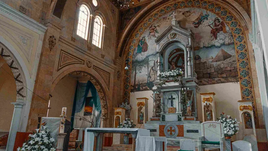 Inside the church, featuring an atrium with a white tablecloth and floral arrangements with white flowers.