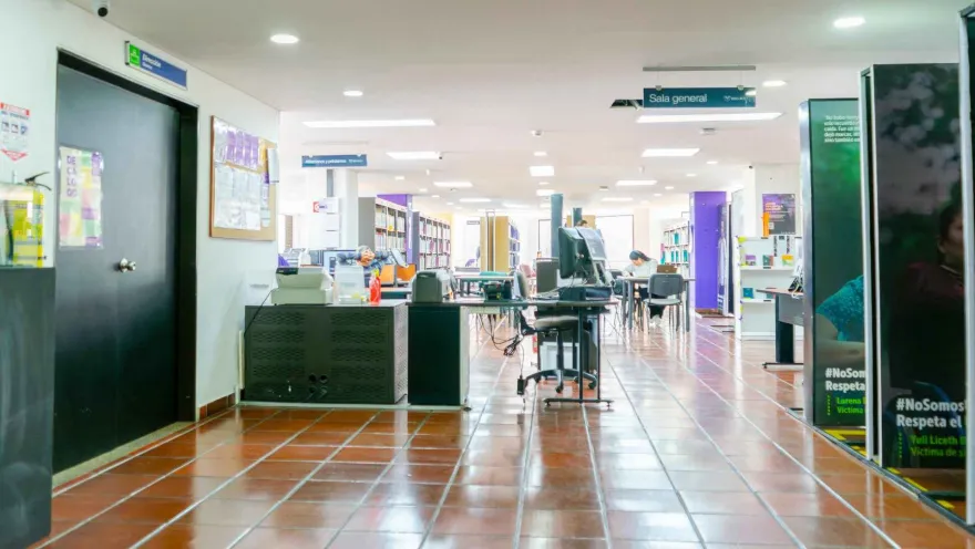 Service and reference area in a library, with service desks, "General Reading Room" signage, and users working in a spacious and organized environment.