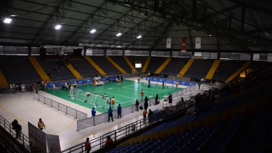 Interior view of the Palacio de los Deportes in Bogotá during a badminton tournament, showing several courts in use and stands surrounding the sports venue.