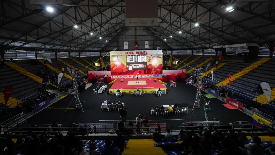 General view of the Palacio de los Deportes in Bogotá during an international weightlifting competition, showing the central platform, stands, and spectators.