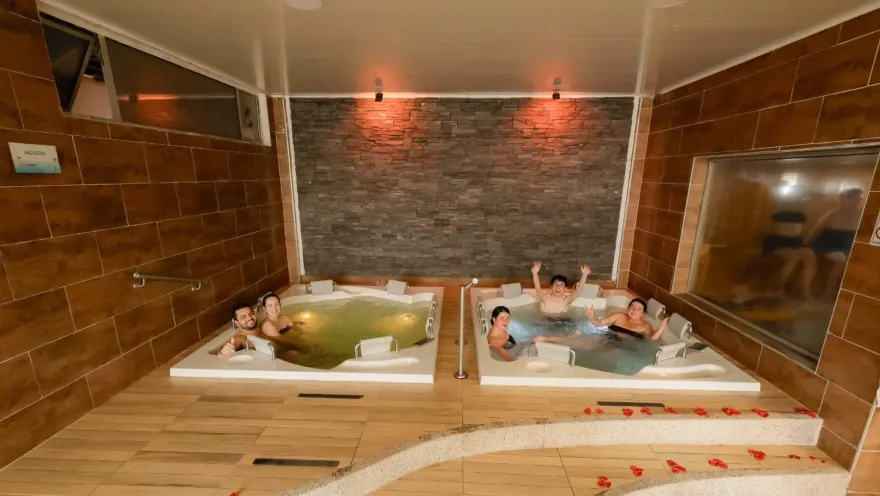  Dos jacuzzis con varias personas disfrutando de un momento de relajación y bienestar en un espacio amplio, cálido y acogedor.