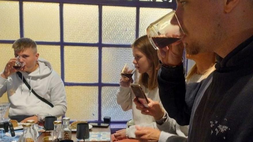 Visitantes participan en una cata de café, degustando diferentes preparaciones mientras exploran sus aromas y sabores en un ambiente acogedor, rodeados de utensilios y métodos de preparación de café de especialidad.