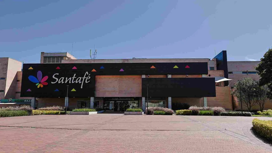  La fachada del Centro Comercial Santafé combina una arquitectura contemporánea con amplios espacios abiertos, jardines y una imagen colorida que refleja el ambiente moderno y familiar del lugar.