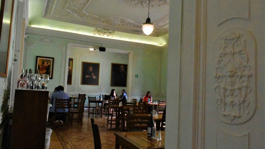 Dining room at La Puerta de la Catedral featuring colonial decor, wooden tables, and diners. 
