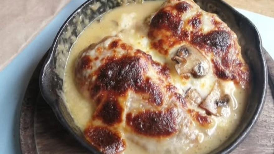 Gratin chicken dish with mushrooms, served in a cast-iron skillet.