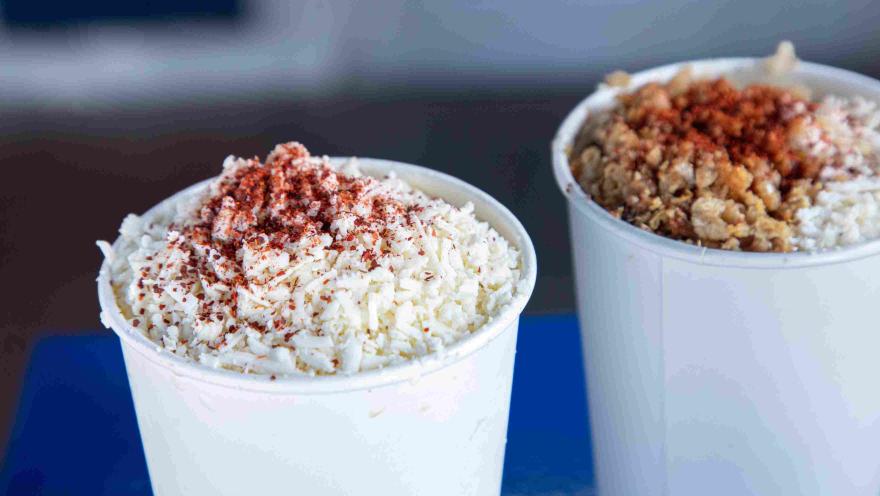 Cups of esquites prepared with cheese and chili powder.