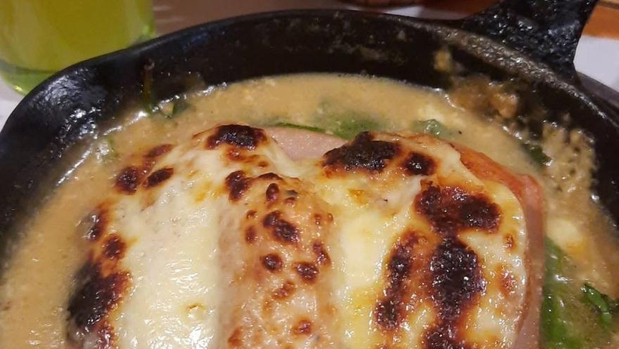 Cheese-gratin chicken served in a creamy sauce in a cast-iron skillet.