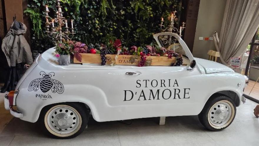 Automóvil clásico blanco decorado con frutas y flores en el interior de Storia D’Amore.
