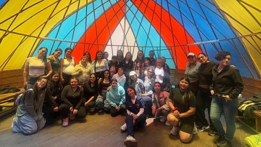 A group of participants poses in a community space decorated with a colorful handcrafted structure.6