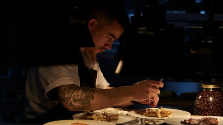  Chef preparando cuidadosamente un plato en la cocina del restaurante El Chato, con atención al detalle y técnicas de alta cocina.
