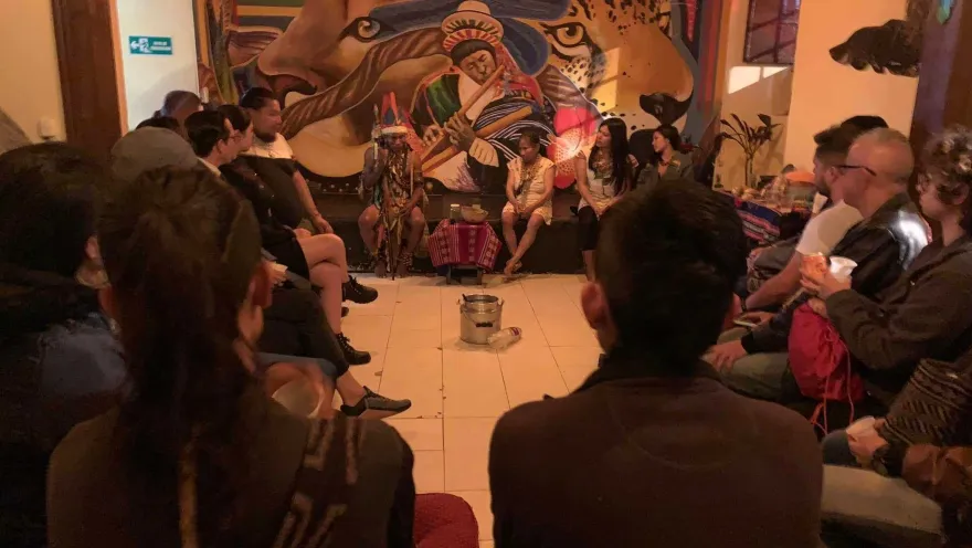 Visitantes participan en un círculo de intercambio cultural, rodeados de expresiones artísticas y símbolos de las culturas ancestrales.