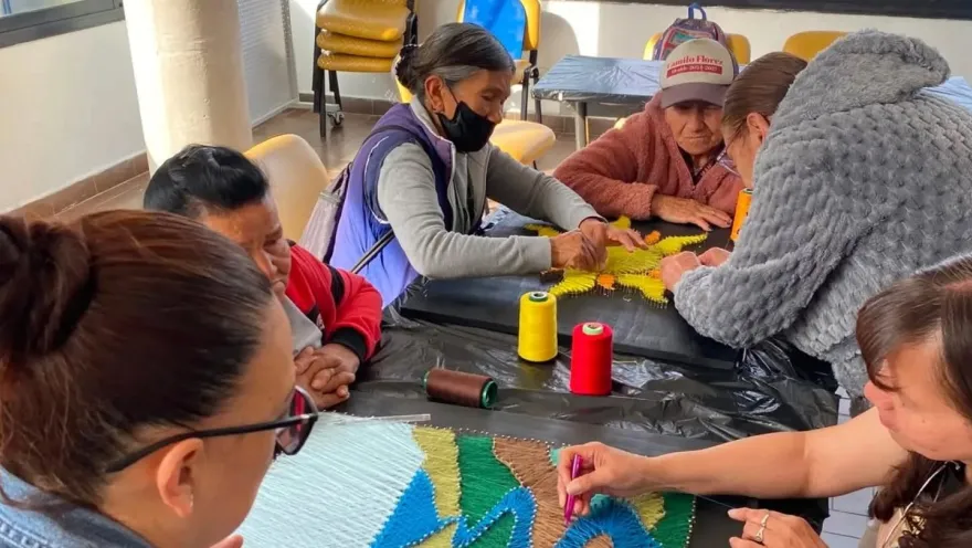 Adults participate in a community workshop on weaving and craft-making.