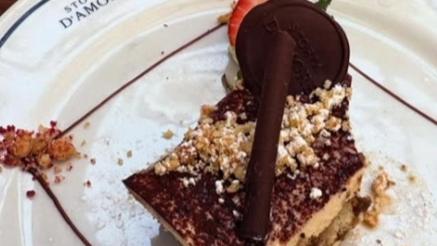 Postre de chocolate decorado con fresa, galleta y chocolate, servido en Storia D’Amore.