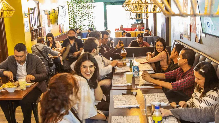 Vista de un comedor concurrido donde varias personas conversan, sonríen y disfrutan de sus alimentos y bebidas.   
