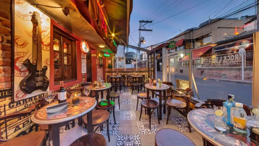 Espacio decorado con motivos de rock & roll, piso de baldosas ornamentadas y mesas redondas cerca a ventanales.