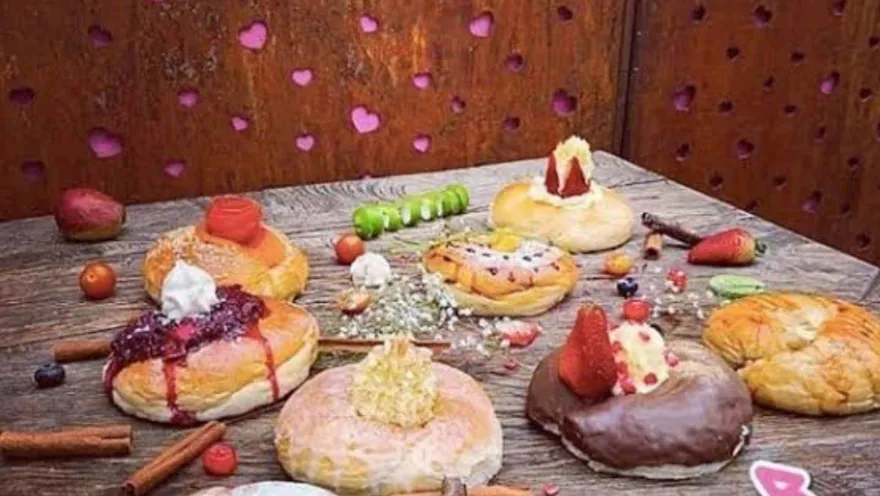 Selección de roscones gourmet dulces y salados decorados con frutas frescas y salsas sobre una mesa rústica de madera.   