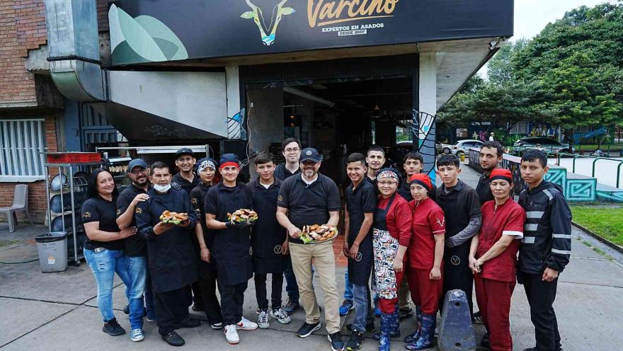 Gran equipo de trabajo con uniformes oscuros y rojos posa sonriente frente al local de asados Varcino.