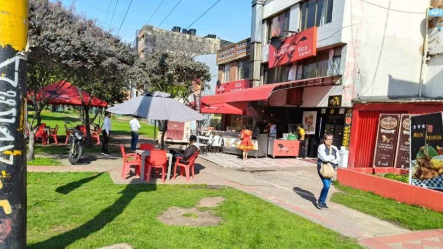 Vista exterior del restaurante Asaderos Alcaraván con mesas, sombrillas y zona verde en un día soleado.