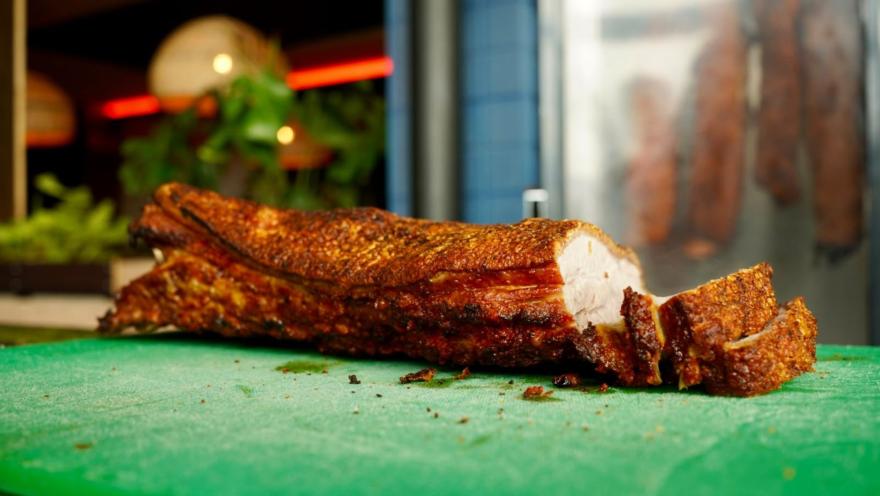 Trozos de chicharrón crujiente y dorado recién cortados sobre una tabla de picar de color verde.