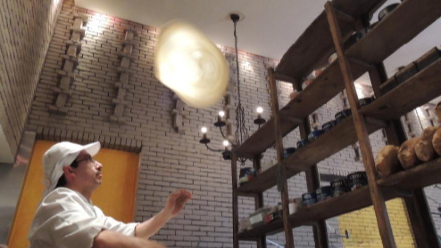 Chef preparando una masa artesanal en el interior de Café Amarti, junto a estanterías con productos e ingredientes.
