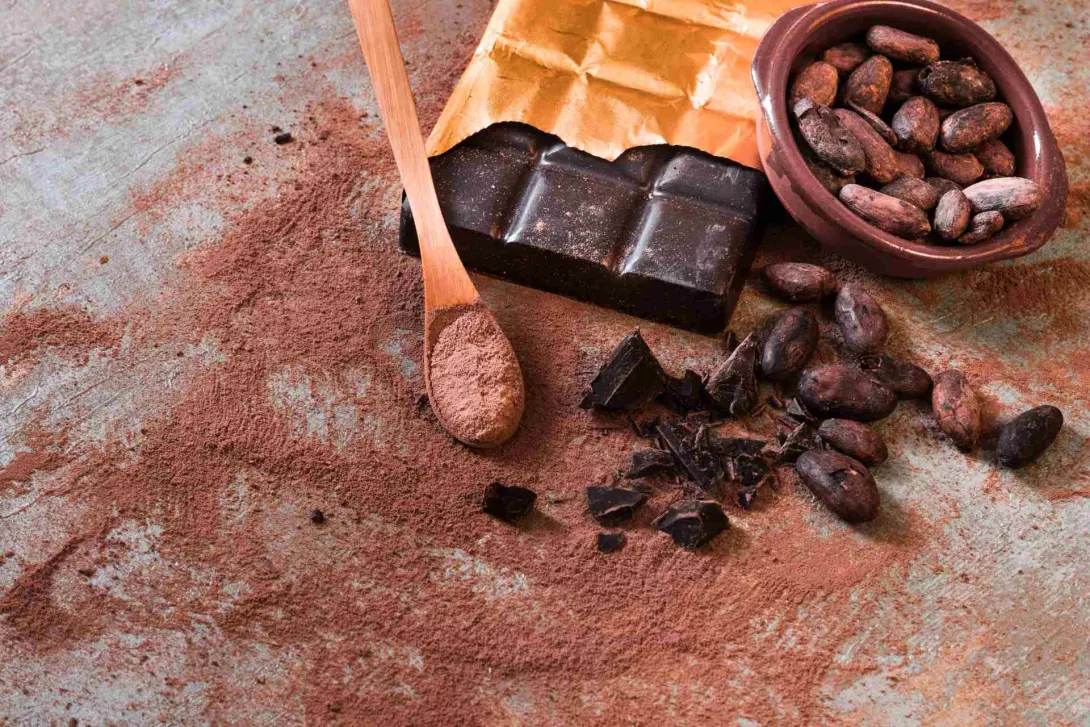 Mesa con residuos y trozos de chocolate. Hay una cuchara negra con chocolate molido.