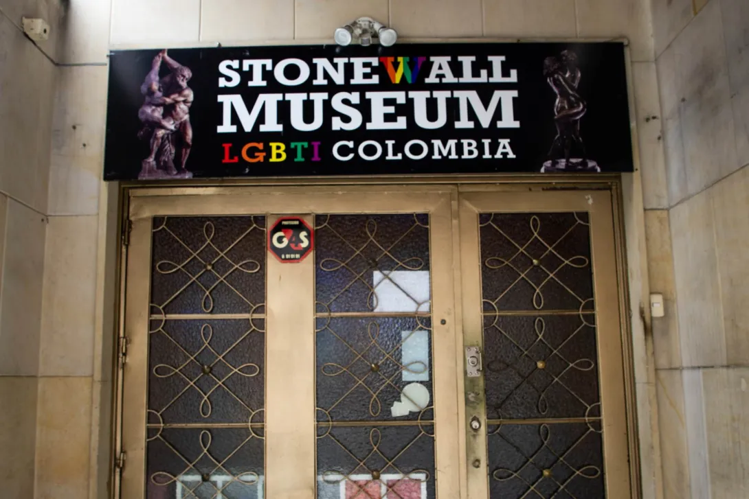 Museo Lgbti primer plano fachada con puerta metálica dorada y aviso en colores que dice Stonewall Museum LGBTI Colombia. El aviso está decorado con imágenes de figuras talladas desnudas y abrazadas.