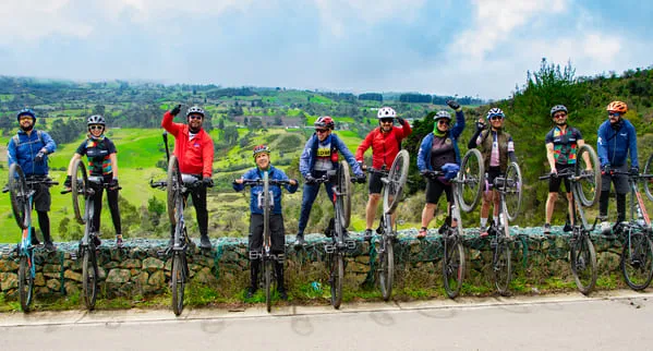 Grupo de ciclistas celebran con un paisaje de montañas de fondo.