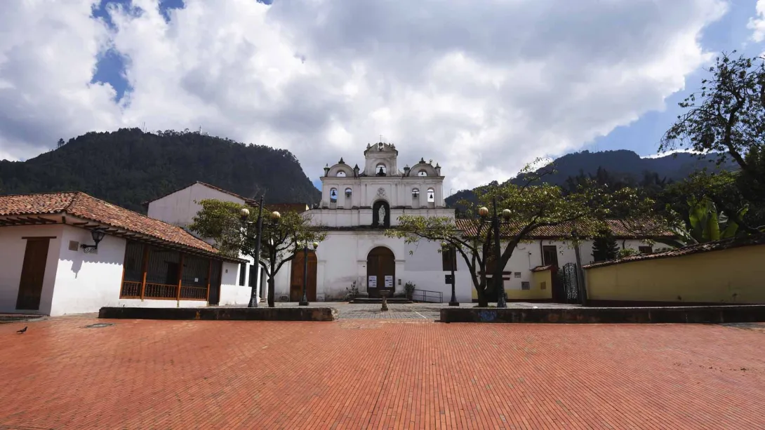 Plazoleta de la Iglesia colonial de las Aguas de día con los cerros orientales de fondo.