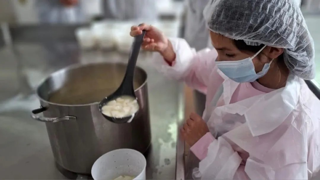 Niño cocinando un queso en una cocina con olla.