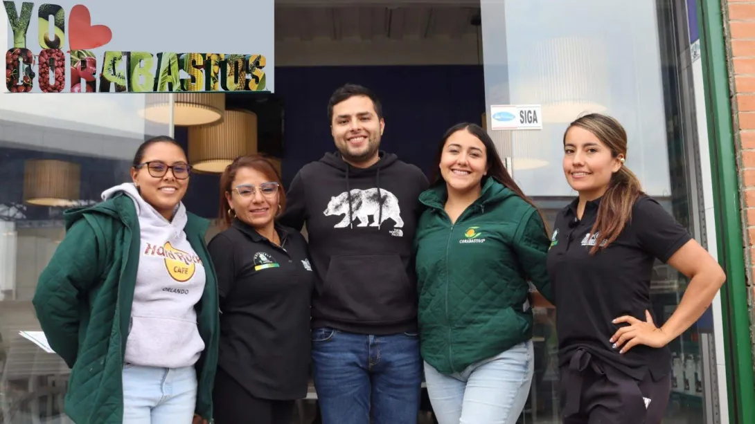 Grupo de cuatro mujeres y un hombre que abrazados sonríen. Hay un logo que dice yo amo Corabastos
