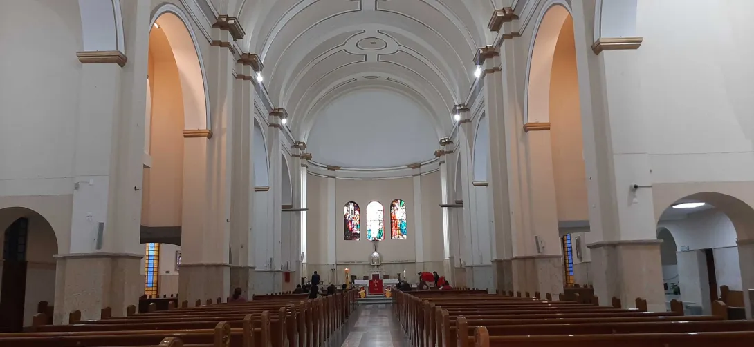 La Iglesia Nuestra Señora de la Valvanera por dentro con sus grandes torres en arcos y techo en forma de óvalos. al fondo se ve el atrio y tres ventanas en óvalos con vitrales.