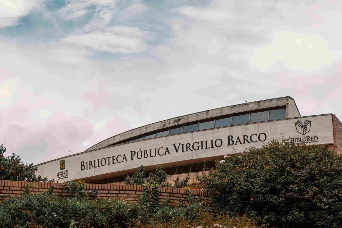 Fachada en ladrillo y piedra en la que resalta el nombre de la Biblioteca Virgilio Barco. El cielo es gris.
