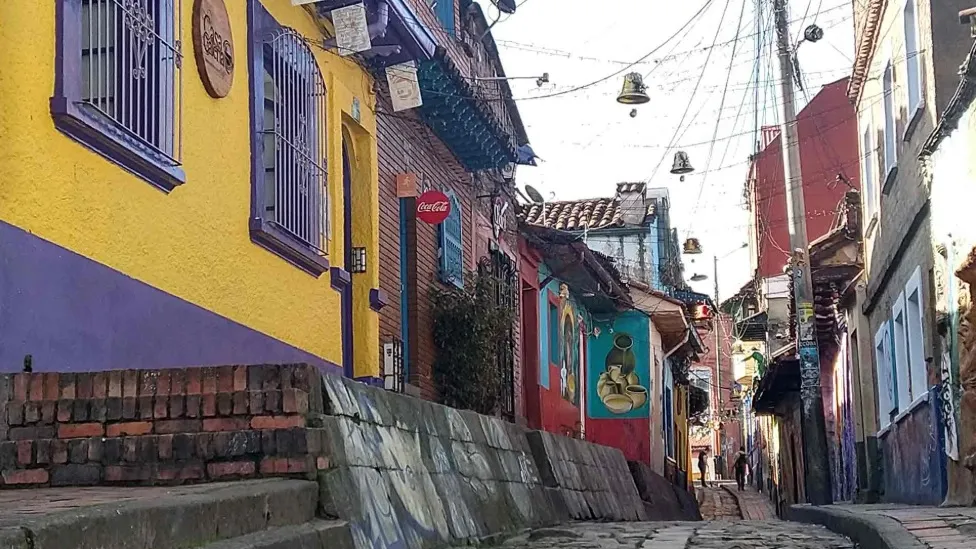  Calle en medio de varias casas antiguas. Las fachadas de las casas llevan vistosos colores.