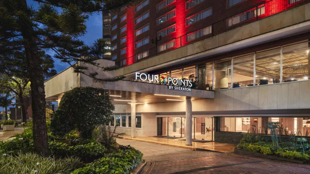 Exterior del hotel Four Points by Sheraton iluminado de noche, con entrada ajardinada.