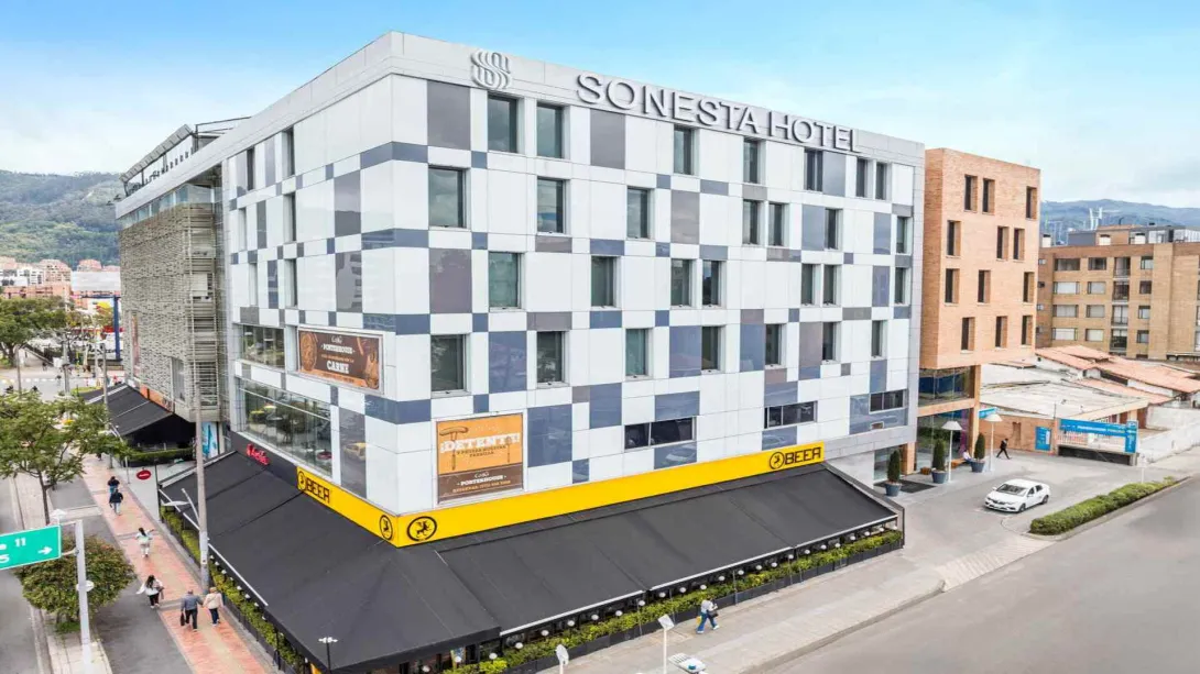 El Sonesta Hotel, un edificio moderno con fachada a cuadros en blanco y gris, ubicado en una zona urbana concurrida.